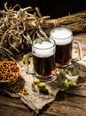 Two tankard beer with wheat and hops , basket of pretzels