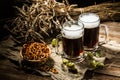 Two tankard beer with wheat and hops , basket of pretzels