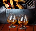 Two tanks of cognac on old brick fireplace with bright fire Royalty Free Stock Photo