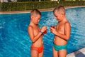 Two tanned short-haired boys stand by the pool and drink a cocktail. Staying in hotel in Turkey Royalty Free Stock Photo