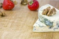 Two tasty pieces of cheese roquefort with walnuts and strawberries on wooden background