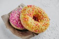 two tasty pink and yellow home made appetizing glazed donuts on kraft paper for delivery  vertical food content  selective focus Royalty Free Stock Photo