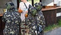 Two teams of paintball players in camouflage form with masks, helmets, guns on the field in the summer. active sport life Royalty Free Stock Photo