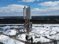 Two technicians working on a telecommunications tower in a snow-covered field. Royalty Free Stock Photo