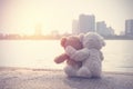 Two teddy bears cute hugging sitting on old floor looking to the city with the sea front side. Royalty Free Stock Photo