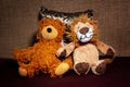 Two teddybears sitting in bed on pillow