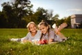 two teen girl friends looking at camera and smiling, have fun on green grass in park. School vloggers wearing casual shirts Royalty Free Stock Photo