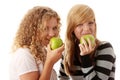 Two teen girlfriends eating green apples Royalty Free Stock Photo