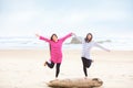 Two teen girls balancing on log at beach Royalty Free Stock Photo