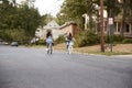 Two teen girls riding bikes in the distance in quiet street