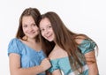 Two teen girls in summer dresses hug and laugh on white background Royalty Free Stock Photo