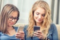 Two teen girs or sisters using smart phones in the living room