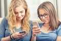 Two teen girs or sisters using smart phones in the living room Royalty Free Stock Photo