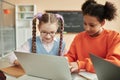 Two teen schoolgirls using laptop in classroom looking at computer screen Royalty Free Stock Photo