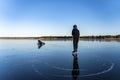 Two teenage boys are ice skating - one fell down and lay on the crystal clear frozen lake, other looking at him and going to help Royalty Free Stock Photo