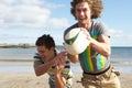 Two Teenage Boys Playing Rugby On Beach