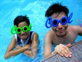 Two teenage boys wearing sunglasses with the word cool for its frame in a swimming pool Royalty Free Stock Photo