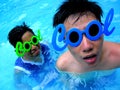 Two teenage boys wearing sunglasses with the word cool for its frame in a swimming pool Royalty Free Stock Photo