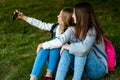 Two teenage girl. Summer in nature. They sit on the grass after school. At a change do Salfi. He takes pictures of Royalty Free Stock Photo