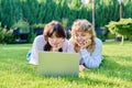Two teenage girlfriends using laptop lying on grass on sunny summer day Royalty Free Stock Photo