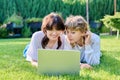 Two teenage girlfriends using laptop lying on grass on sunny summer day Royalty Free Stock Photo