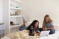 Two teenage girls on bed using laptop computer Royalty Free Stock Photo