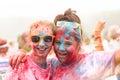 Two teenage girls earing sunglasses covered in paint celebrate completing a Colour Paint Run for charity