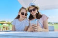 Two teenage girls in headphones listening music on smartphone, having fun Royalty Free Stock Photo