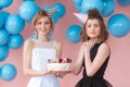 Two teenage girls holding birthday cake. Wearing black and white dresses and hats Royalty Free Stock Photo