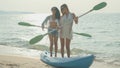 Two teenage girls holding oars and standing dancing on the beach on their summer vacations, smiling and happy on vacation Royalty Free Stock Photo