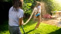 Two teenage girls playing water fight and splashing water from garden hose Royalty Free Stock Photo