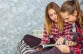 Two Teenage Girls reading fashion Magazine sitting on a couch at home Royalty Free Stock Photo