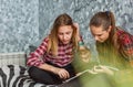 Two Teenage Girls reading fashion Magazine sitting on a couch at home Royalty Free Stock Photo