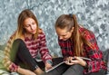 Two Teenage Girls reading fashion Magazine sitting on a couch at home Royalty Free Stock Photo