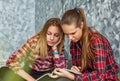Two Teenage Girls reading fashion Magazine sitting on a couch at home Royalty Free Stock Photo
