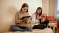 Two teenage girls sitting on bed and using tablet computers. Education and new learning technology from home. Royalty Free Stock Photo