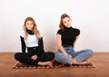 Two teenage girls sitting on oriental carpet