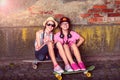 Two teenage girls sitting on a skateboard and smiling Royalty Free Stock Photo