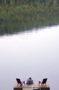 Pair of teenage girls sitting on wooden dock at lake with copy space Royalty Free Stock Photo