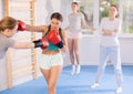 Two teenage girls in sportswear are engaged in boxing sparring in the gym under guidance of trainer in gym Royalty Free Stock Photo