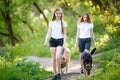 Two teenage girls walking with her dogs in park Royalty Free Stock Photo