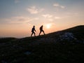 Two teenage hikers walking enjoying a view while the sun setting down