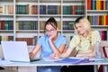 Two teenage schoolgirls students sitting with a laptop in the library Royalty Free Stock Photo