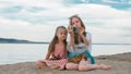 Two teenage are sitting on a sandy beach, on the Internet in phone. Royalty Free Stock Photo