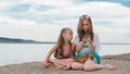 Two teenage are sitting on a sandy beach, on the Internet in phone. Royalty Free Stock Photo