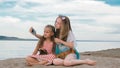 Two teenage are sitting on a sandy beach, on the Internet in phone. Royalty Free Stock Photo