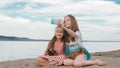 Two teenage are sitting on a sandy beach, on the Internet in phone. Royalty Free Stock Photo