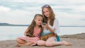 Two teenage are sitting on a sandy beach, on the Internet in phone. Royalty Free Stock Photo