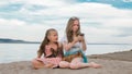 Two teenage are sitting on a sandy beach, on the Internet in phone. Royalty Free Stock Photo