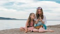 Two teenage are sitting on a sandy beach, on the Internet in phone. Royalty Free Stock Photo